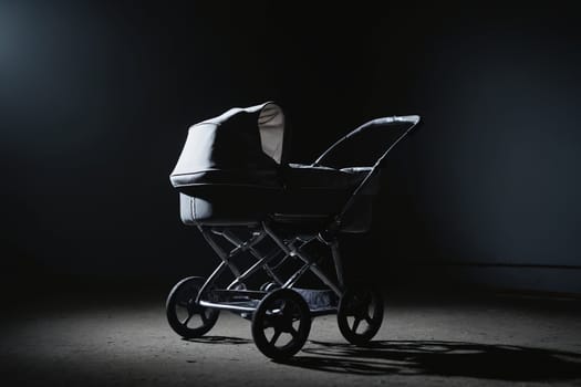 A relic of a bygone era, an old-fashioned baby stroller, manifests a poignant memory in this black and white image. The isolation, accentuated by the gallery-style single light source, elicits an intense and somewhat melancholic ambiance of yesteryears.