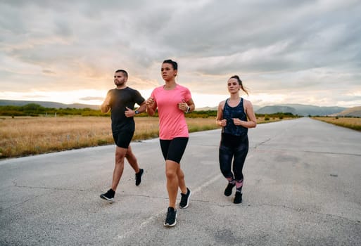 In a breathtaking scene of nature's beauty, an athlete leads a group run at sunset, inspiring and motivating her companions with her leadership and determination