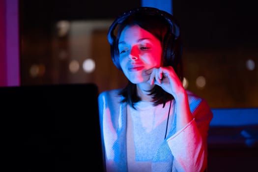 A young girl holds headphones and is listening and composing music, a woman sits with a laptop by the window in her room, works and enjoys the sound.