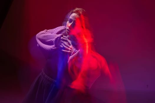 A young woman dances contemporary dances in blue and red light. Long exposure photo