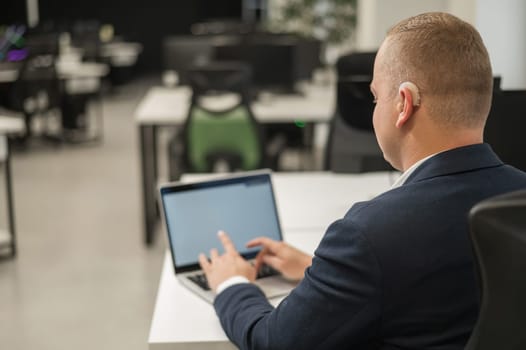 Caucasian deaf man typing on laptop in office