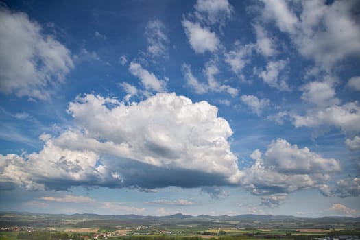 Beauty cloud against a blue sky background. Sky slouds. Blue sky with cloudy weather, nature cloud over the landskape. Over the land white clouds, blue sky and sun. High quality photo