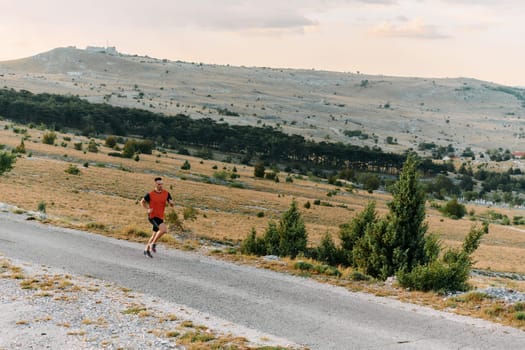 A muscular male athlete runs along a rugged mountain path at sunrise, surrounded by breathtaking rocky landscapes and natural beauty.