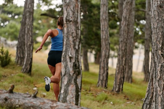 An intrepid woman fearlessly navigates through perilous forest terrain, effortlessly leaping over wooden obstacles with determination and grace, showcasing her adventurous spirit and athletic prowess