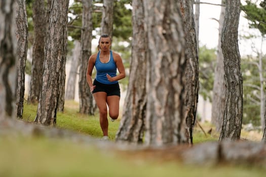 An intrepid woman fearlessly navigates through perilous forest terrain, effortlessly leaping over wooden obstacles with determination and grace, showcasing her adventurous spirit and athletic prowess