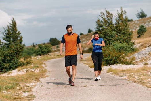 Couple running in nature at morning wearing protective face masks.