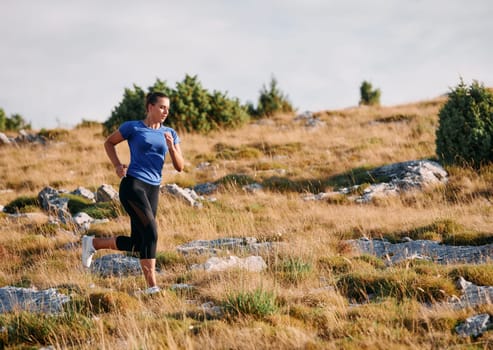 A determined female athlete runs through a forest trail at sunrise, surrounded by breathtaking natural beauty and vibrant greenery.