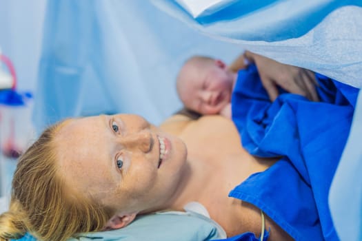 Baby on mother's chest immediately after birth in a hospital. The mother and newborn share a tender moment, emphasizing the bond and emotional connection. The medical staff ensures a safe and caring environment.