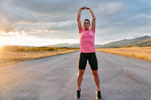 A lone athlete is captured stretching gracefully against the backdrop of a stunning sunset, her silhouette a testament to dedication and resilience after an intense run