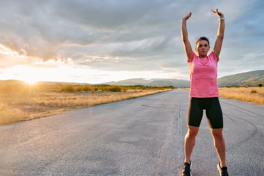 A lone athlete is captured stretching gracefully against the backdrop of a stunning sunset, her silhouette a testament to dedication and resilience after an intense run