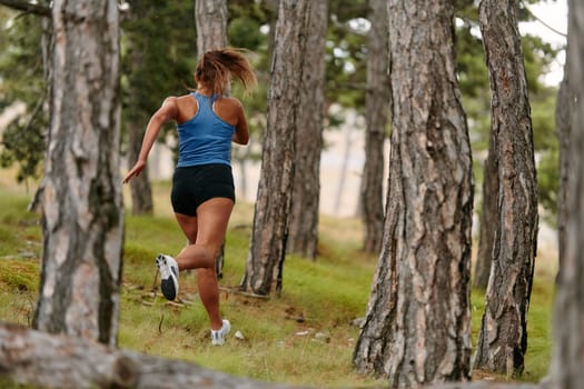 An intrepid woman fearlessly navigates through perilous forest terrain, effortlessly leaping over wooden obstacles with determination and grace, showcasing her adventurous spirit and athletic prowess