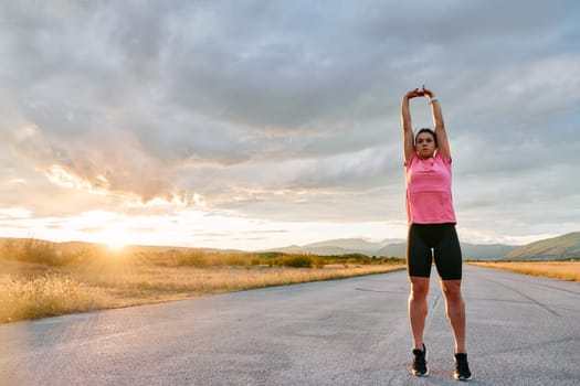 A lone athlete is captured stretching gracefully against the backdrop of a stunning sunset, her silhouette a testament to dedication and resilience after an intense run