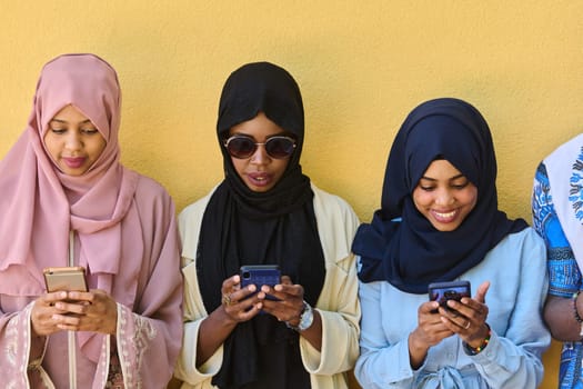 A diverse group of teenagers standing together against a wall, engrossed in their smartphones, showcasing modern connectivity and social interaction.