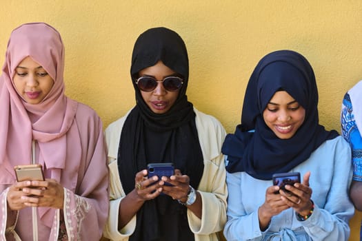 A diverse group of teenagers standing together against a wall, engrossed in their smartphones, showcasing modern connectivity and social interaction.