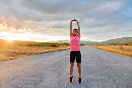 A lone athlete is captured stretching gracefully against the backdrop of a stunning sunset, her silhouette a testament to dedication and resilience after an intense run
