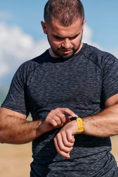 An athletic man checks the results of his run on a smartwatch, leveraging technology to monitor his performance and progress in his fitness journey