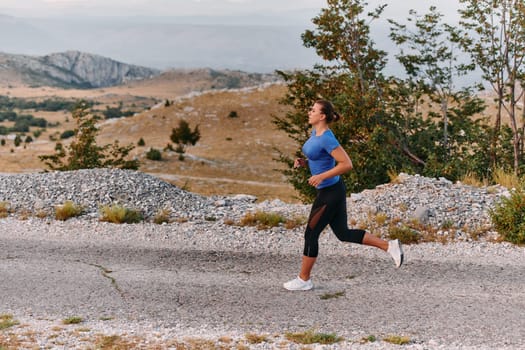 A determined female athlete runs through a forest trail at sunrise, surrounded by breathtaking natural beauty and vibrant greenery.