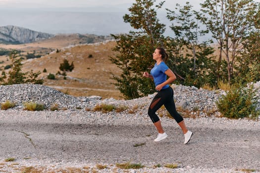 A determined female athlete runs through a forest trail at sunrise, surrounded by breathtaking natural beauty and vibrant greenery.