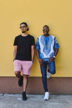 A depiction of camaraderie and cultural diversity two male friends, one an African American teenager dressed in Sudanese traditional attire, leaning against a vibrant yellow wall