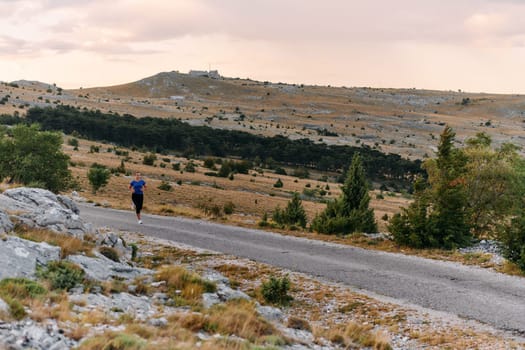 A determined female athlete runs through a forest trail at sunrise, surrounded by breathtaking natural beauty and vibrant greenery.