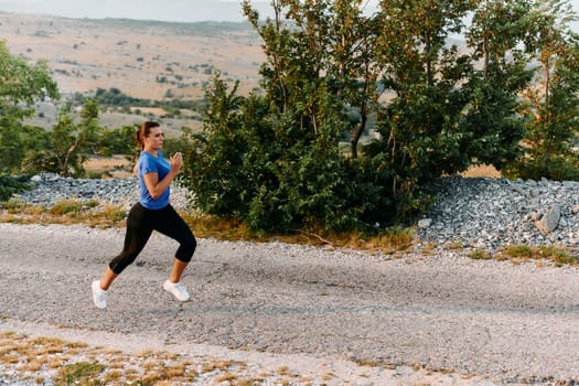 A determined female athlete runs through a forest trail at sunrise, surrounded by breathtaking natural beauty and vibrant greenery.