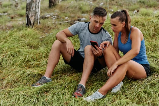 A romantic couple sits in the forest, browsing new running routes on their smartphone, embracing the beauty of nature as they plan their next outdoor adventure together