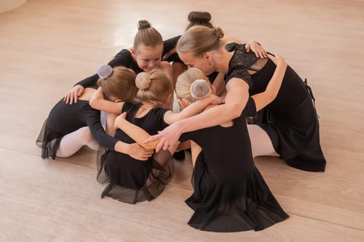 Five little ballerinas and a teacher are sitting in a circle hugging