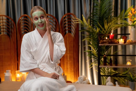 Serene ambiance of spa salon, woman customer indulges in rejuvenating with luxurious face cream massage with warm lighting candle. Facial skin treatment and beauty care concept. Quiescent