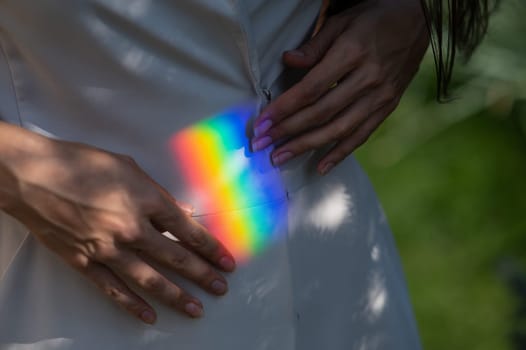 Faceless woman catching rainbow ray with her hands outdoors