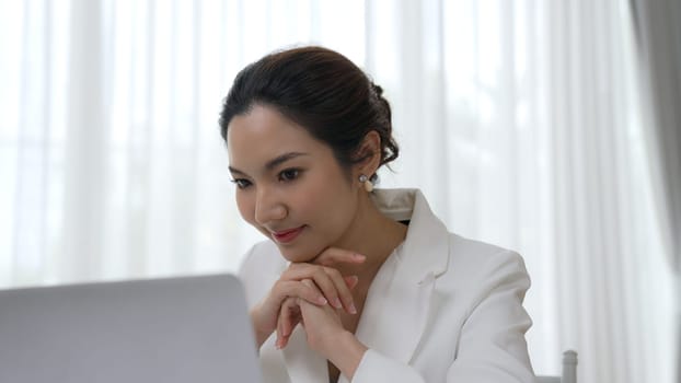 Young businesswoman sitting on the workspace desk using laptop computer for internet online content writing or secretary remote working from home. Vivancy