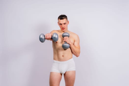 Shirtless bodybuilder holding a dumbell and showing his muscular arms.