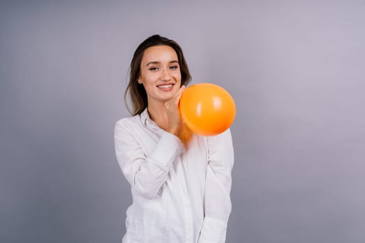 Portrait of beautiful woman with ballon in hands on grey background in studio