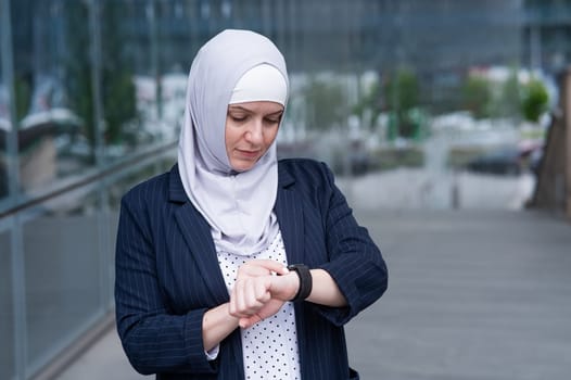 Business woman in hijab and suit uses smart watch