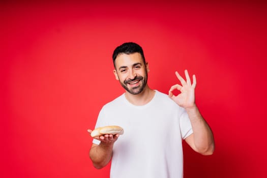 Man holding freshly baked bread in hands isolated on a red background