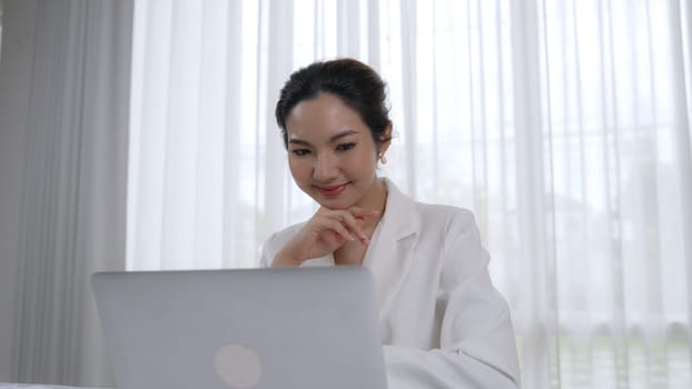 Young businesswoman sitting on the workspace desk using laptop computer for internet online content writing or secretary remote working from home. Vivancy