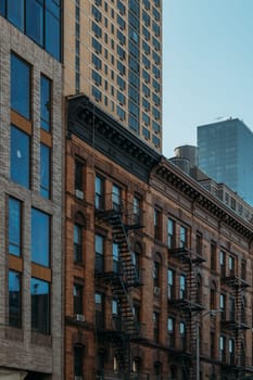 A blend of historic New York City buildings featuring classic fire escapes contrasting with a modern high-rise in the background.