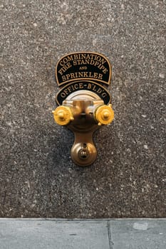 Close-up of a combination fire standpipe and sprinkler system attached to an office building wall in New York City.