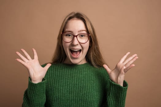 This description depicts a young woman with glasses and a green sweater, expressing surprise on her face