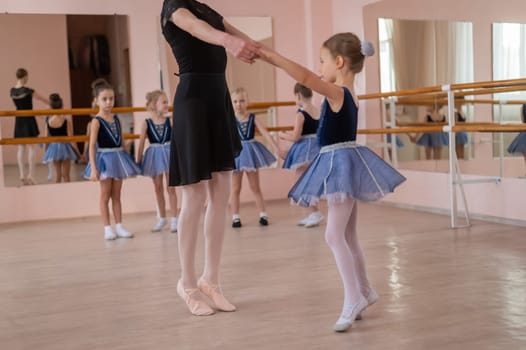 Children's ballet school. Caucasian woman teaching ballet to little girls