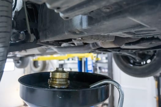 A mechanic drains a car's used engine oil