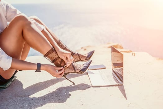 Happy girl doing yoga with laptop working at the beach. beautiful and calm business woman sitting with a laptop in a summer cafe in the lotus position meditating and relaxing. freelance girl remote work beach paradise