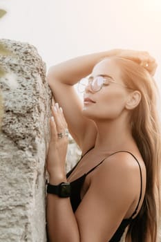 Woman travel sea. Young Happy woman in a long red dress posing on a beach near the sea on background of volcanic rocks, like in Iceland, sharing travel adventure journey