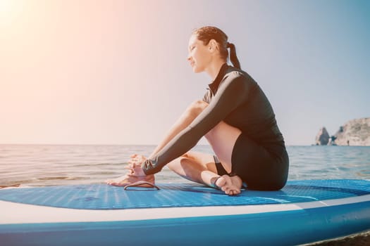 Woman sup yoga. Middle age sporty woman practising yoga pilates on paddle sup surfboard. Female stretching doing workout on sea water. Modern individual hipster outdoor summer sport activity