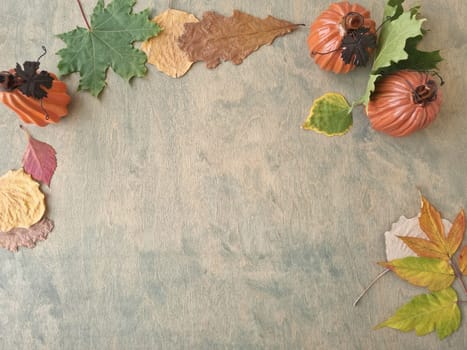 Halloween background. autumn leaves, ceramic orange pumpkins on green wooden background with copy space. flat lay, top view