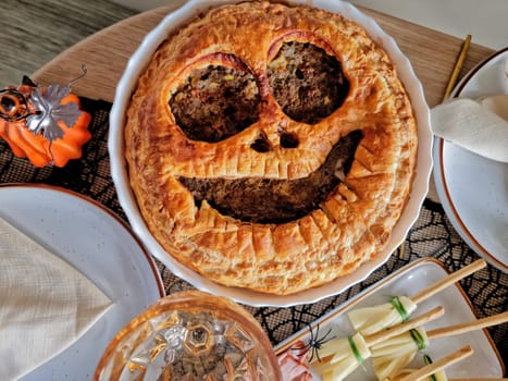 table setting for a Halloween party. Appetizing, rosy, baked meat pie in the shape of Jack O'Lantern. flat lay, top view