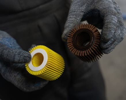 Mechanic holding old and new car oil filters