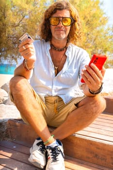 Man with credit card and cell phone in his hands outdoors. Concept: Online Shopping.