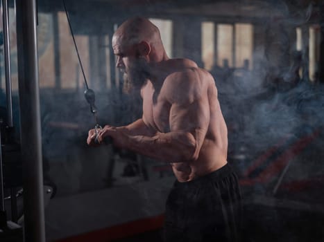 Bald Caucasian Bodybuilder doing heavy triceps exercises with cable