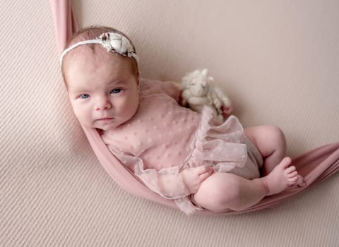 Newborn Baby Girl Sleeps In Hammock During Studio Photo Session