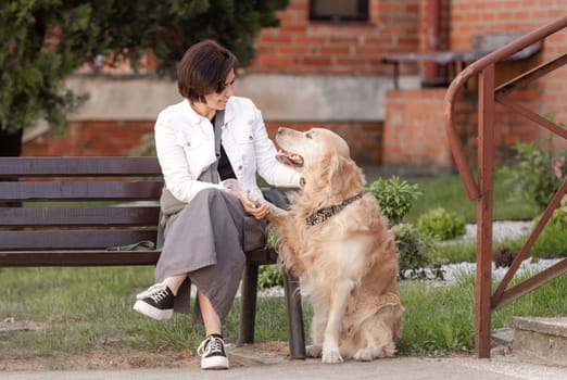 Golden Retriever Gives Paw To Its Owner Near House In Summer